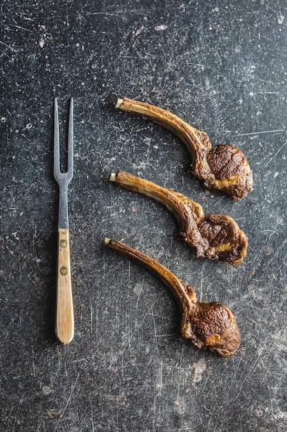 7 Benefícios Surpreendentes das Carnes de Cordeiro - Confira! 1 Uma Vista De Cima De Deliciosos Chops De Cordeiro Grelhados Lindamente Dispostos Em Uma Mesa Preta, Decorados Com Ervas E Especiarias.