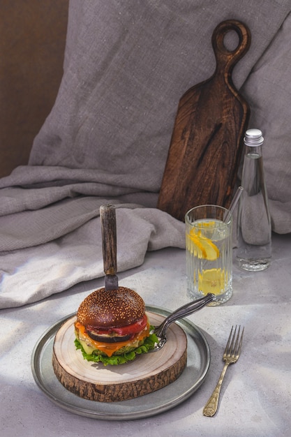 Como Fazer Receitas De Hambúrguer Artesanal: Dicas Imperdíveis (2024) 1 Uma Apresentação Rústica De Um Hambúrguer Vegetariano Com Espinafre, Acompanhado De Uma Bebida De Limão, Servido Em Uma Mesa De Madeira.