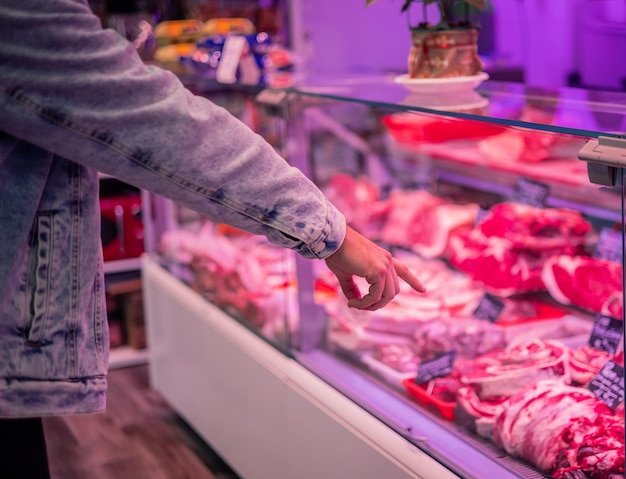 Um Cliente Apontando Para Vários Produtos De Carne Em Um Açougue, Mostrando A Seleção Disponível Em Uberlândia.