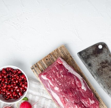 Uma Vista De Cima De Um Filé Mignon De Carne Bovina Fresca, Temperado Com Sal, Grãos De Pimenta E Tomilho, Colocado Sobre Uma Superfície De Madeira Ao Lado De Dentes De Alho.