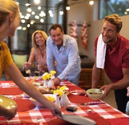 Uma Família Caucasiana Multigeracional Reunida Em Torno De Uma Mesa De Jantar, Sorrindo E Conversando Enquanto Preparavam A Mesa Para O Jantar.
