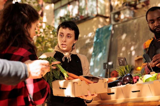 Os Benefícios de Optar por Carnes Frescas e Locais em Uberlândia 1 Uma Jovem, Vestindo Um Avental, Está Em Uma Feira Livre Segurando Uma Caixa De Papelão Cheia De Frutas E Vegetais Frescos E Orgânicos, Exibindo Alimentos De Origem Local.